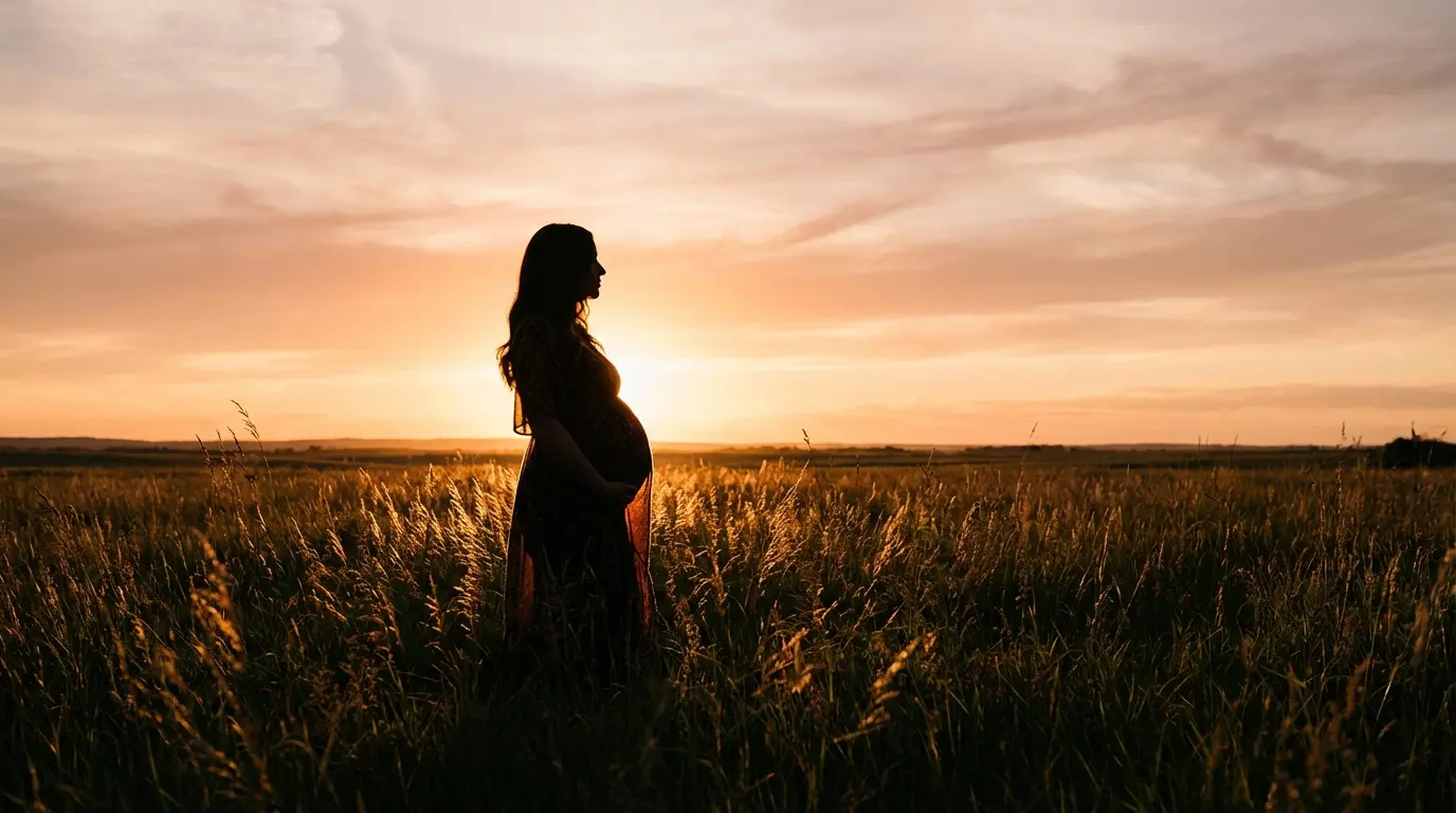 silhouette of a pregnant woman standing in a field at golden hour with light surrounding her, symbolizing spiritual creation and transformation