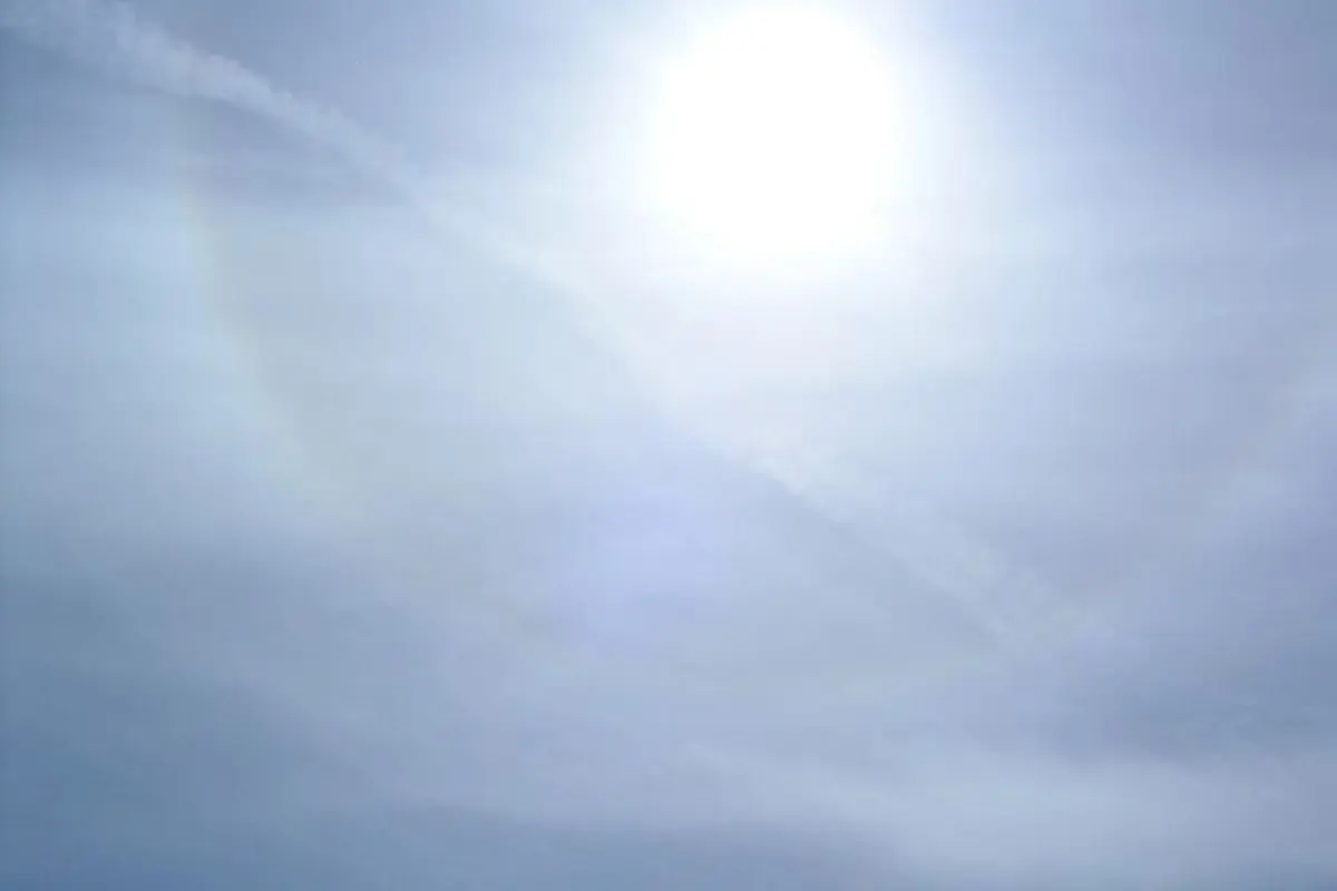 Cirrostratus clouds spreading across a pale blue sky around the sun